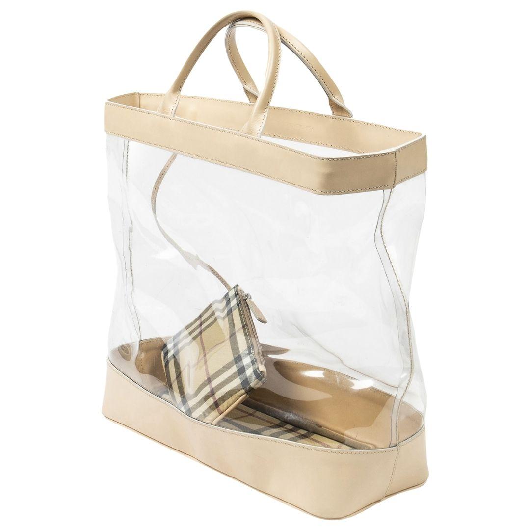 Transparency meets elegance with this beige/transparent PVC large clear tote. Crafted from durable PVC, this tote showcases a sleek beige and transparent color palette. The beige leather straps provide a touch of luxury, while the silver hardware