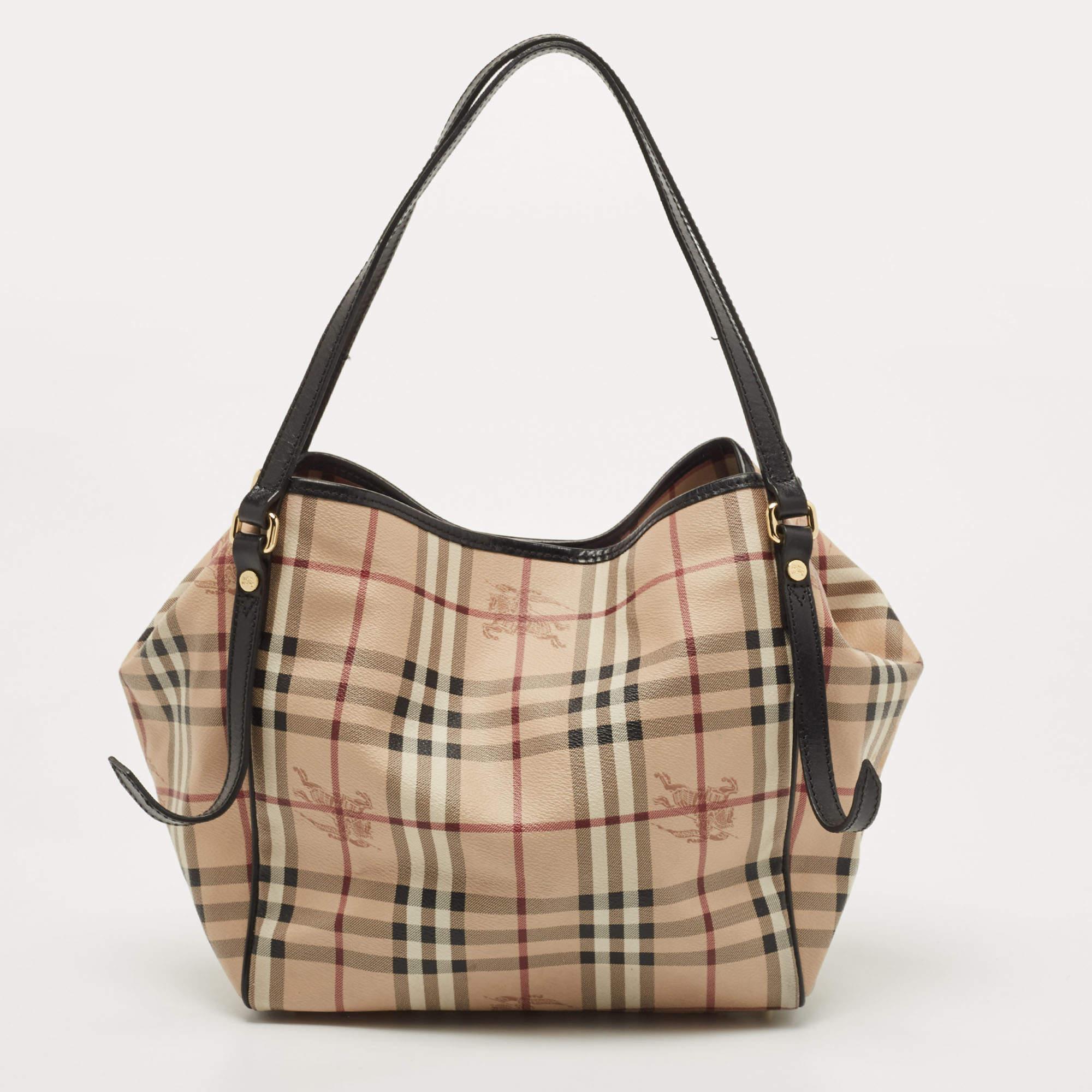 This Canterbury tote from Burberry is crafted from their signature Haymarket check PVC and enhanced with leather. It comes with dual flat handles, protective metal feet, and a canvas-lined interior that can hold all your daily necessities. Simple in