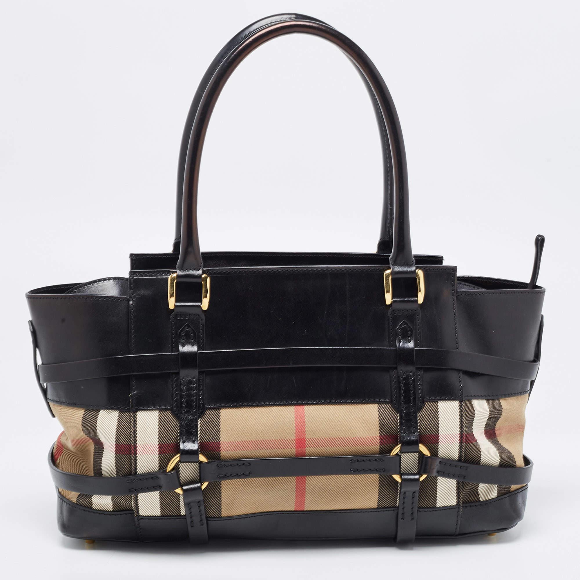 Diese schicke und modische Burberry Satchel hat das Flair, um jeden Look zu vervollständigen. Sie ist aus Canvas und Leder gefertigt und verfügt über den klassischen House-Karomuster sowie über Gürteldetails. Diese Umhängetasche ist mit zwei oben