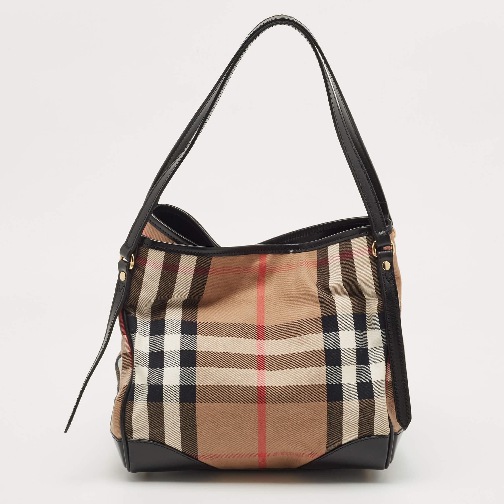 This Burberry Canterbury tote has the perfect fusion of ease and style. Created from House Check fabric and leather, it is held by dual handles at the top, and it is adorned with gold-tone accents. The fabric-lined interior of the bag is spacious