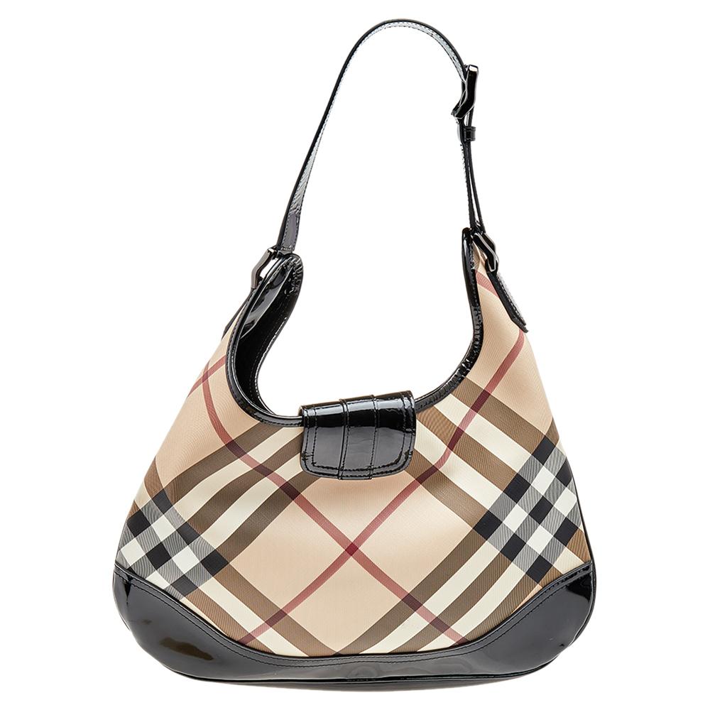 This Brooke hobo bag from the luxury fashion house exudes unmatched elegance. It is crafted from Burberry’s signature check PVC and patent leather. It has a buckle flap closure and flat shoulder handle with a buckled detail. Its fabric-lined