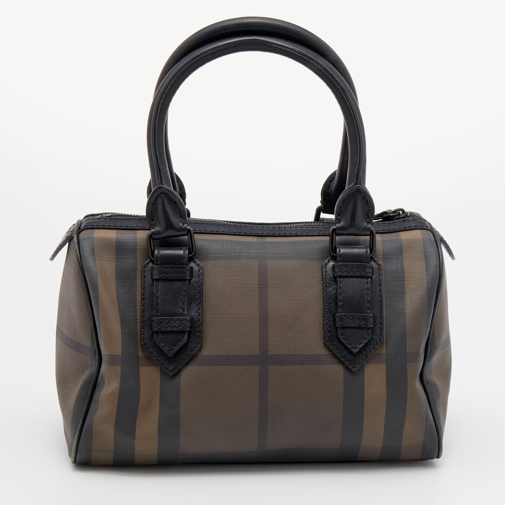 Ideal for everyday use, this Burberry Chester Duffel bag is stylish and light. It is crafted in Smoke Check canvas and paired with two top handles, leather trims, and black-tone hardware. It has a top zipper closure to secure the canvas-lined