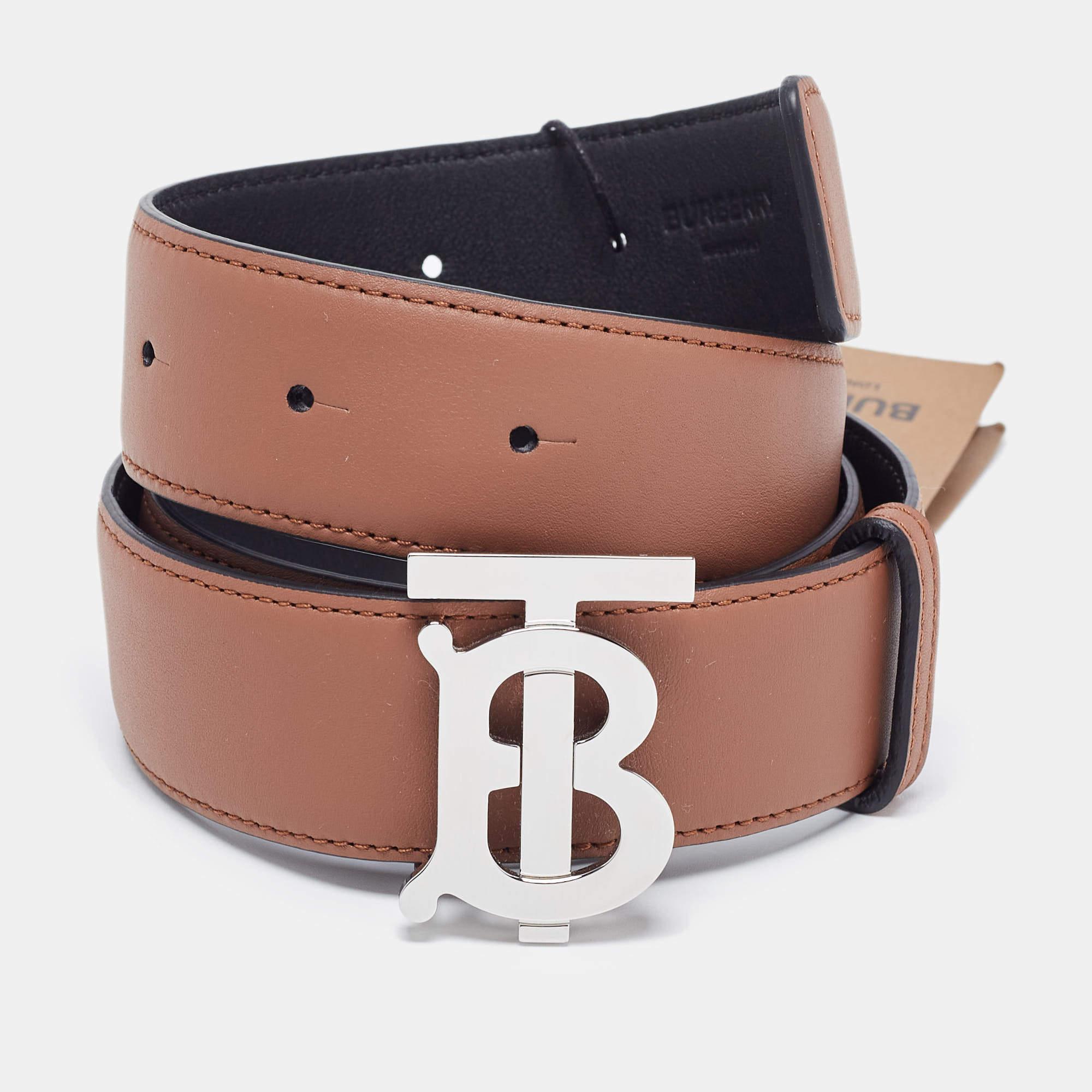 The Burberry belt is a versatile and stylish accessory. Crafted from high-quality leather, it features a reversible design with black and brown sides. The iconic TB logo is prominently displayed on the polished silver-tone buckle, making it a