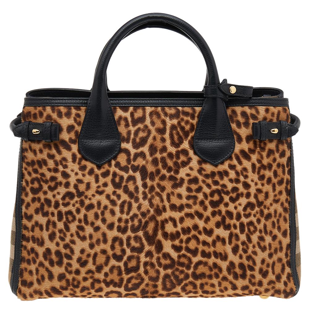 How chic and sophisticated is this bag from Burberry! This brown and black leopard print creation is crafted from leather and calfhair and styled with the signature House check panels on the sides. It flaunts dual-rolled handles, a detachable