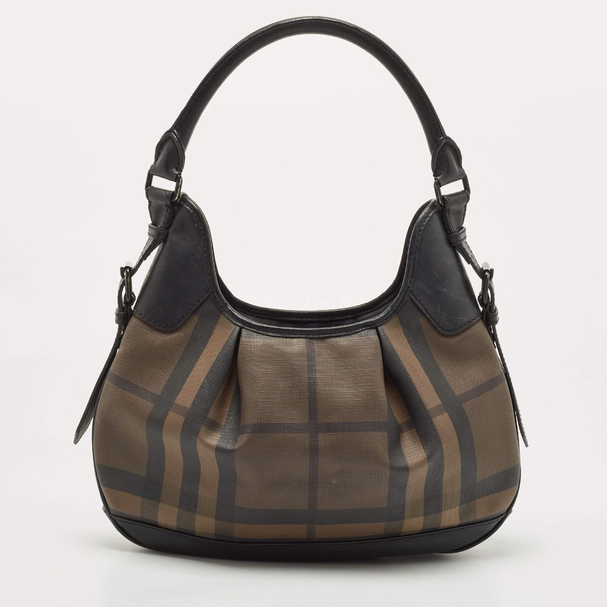Spacious and captivating, this Brooklyn hobo is from the House of Burberry. It has been crafted from House Check PVC and leather on the exterior. It features two handles, black-tone hardware, and a canvas-lined interior. Make this hobo yours today!

