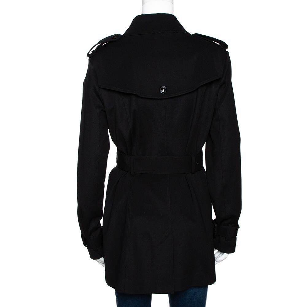 Always feel in sync with classic fashion with this Burberry coat. This black piece will make a fashionable add-on over any outfit. It is tailored from durable materials and designed with a double breasted front. The belt adds the perfect finishing