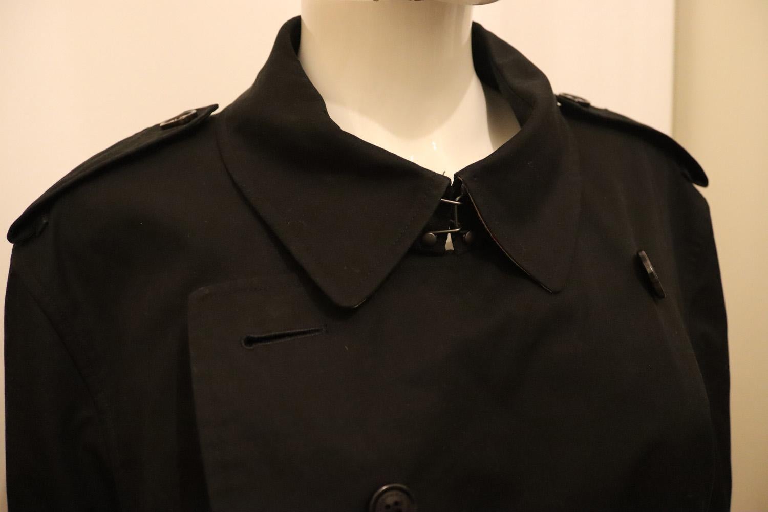 The iconic Burberry trench coat , made in England from shower resistant cotton gabardine. Inside is Burberry check cotton used to line the coats since the 1920s. Part of the Burberry Heritage collection.  The coat has double breasted button closure