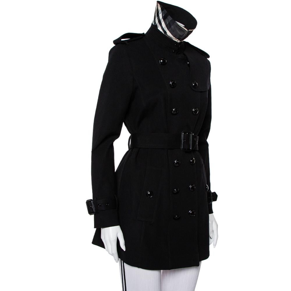Burberry is known for its trench coats. This creation exudes elegance and is great for casual wear. Crafted from knit fabric, this trench coat comes in black. It features a simple collar, button closure, two external pockets, a belt that rests on