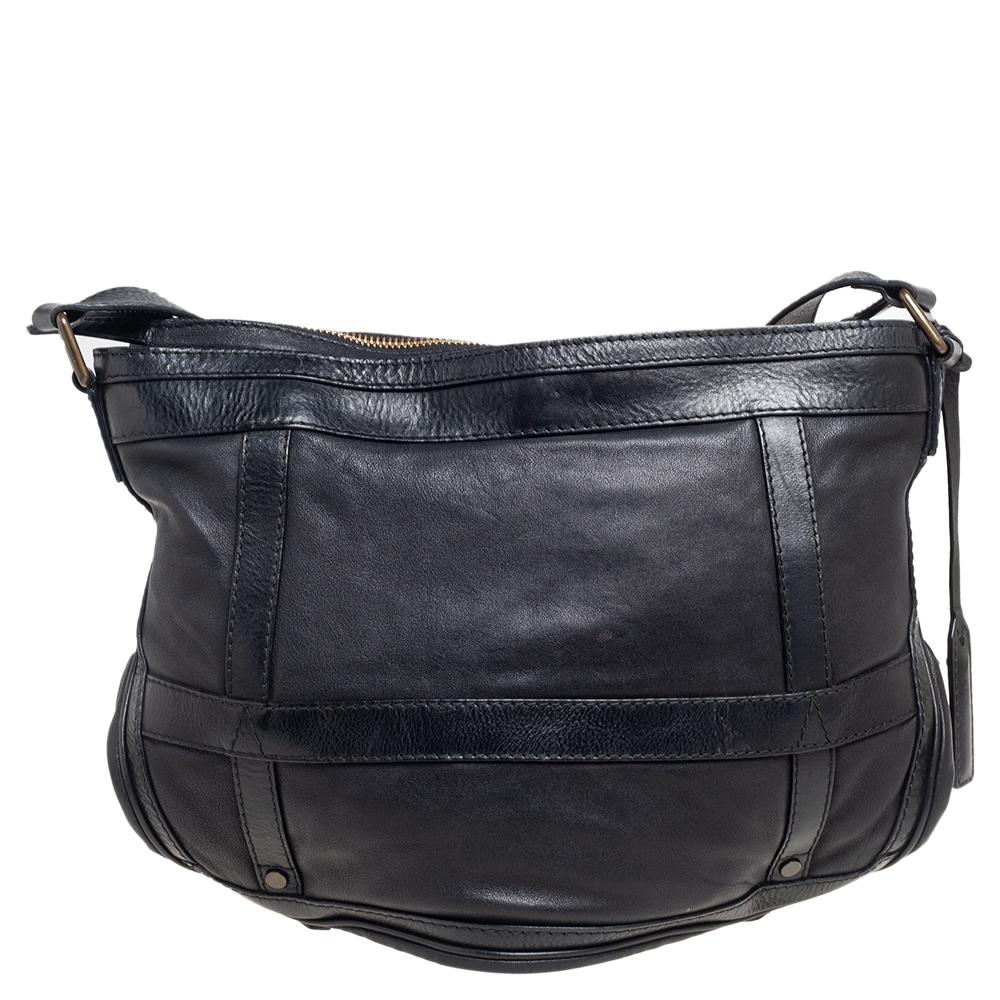 This uber-cool messenger bag is by Burberry. It is made from black leather and features an adjustable shoulder strap and buckled leather trims. The interior is lined with fabric it is secured with a top zip closure and houses a patch pocket with