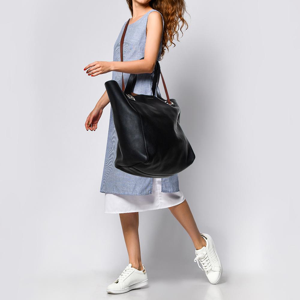 This striking tote comes from the iconic house of Burberry. It has been meticulously crafted in Italy and made from quality leather. It comes in a classic shade of black. It has dual shoulder handles accented with large grommet detailing and an