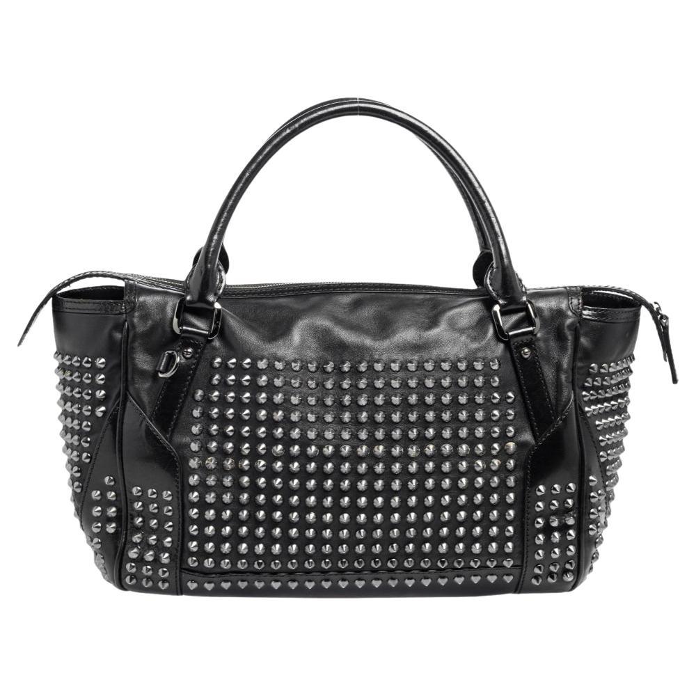 This chic Edenham tote bag is a Burberry classic. It is made from leather comes with double rolled leather handles and is highlighted with studs that add an edgy appeal. The bag is finished with nylon- lined interior that houses two compartments,