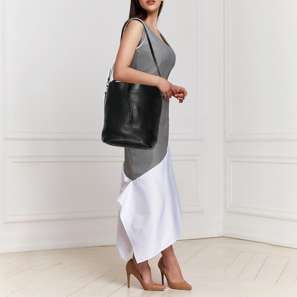 This wonderful Burberry design is made from leather and enhanced with silver-tone hardware. The bag has a spacious shape with a drawstring closure that secures the fabric interior. Complete with two different handles, it is an apt accessory to carry