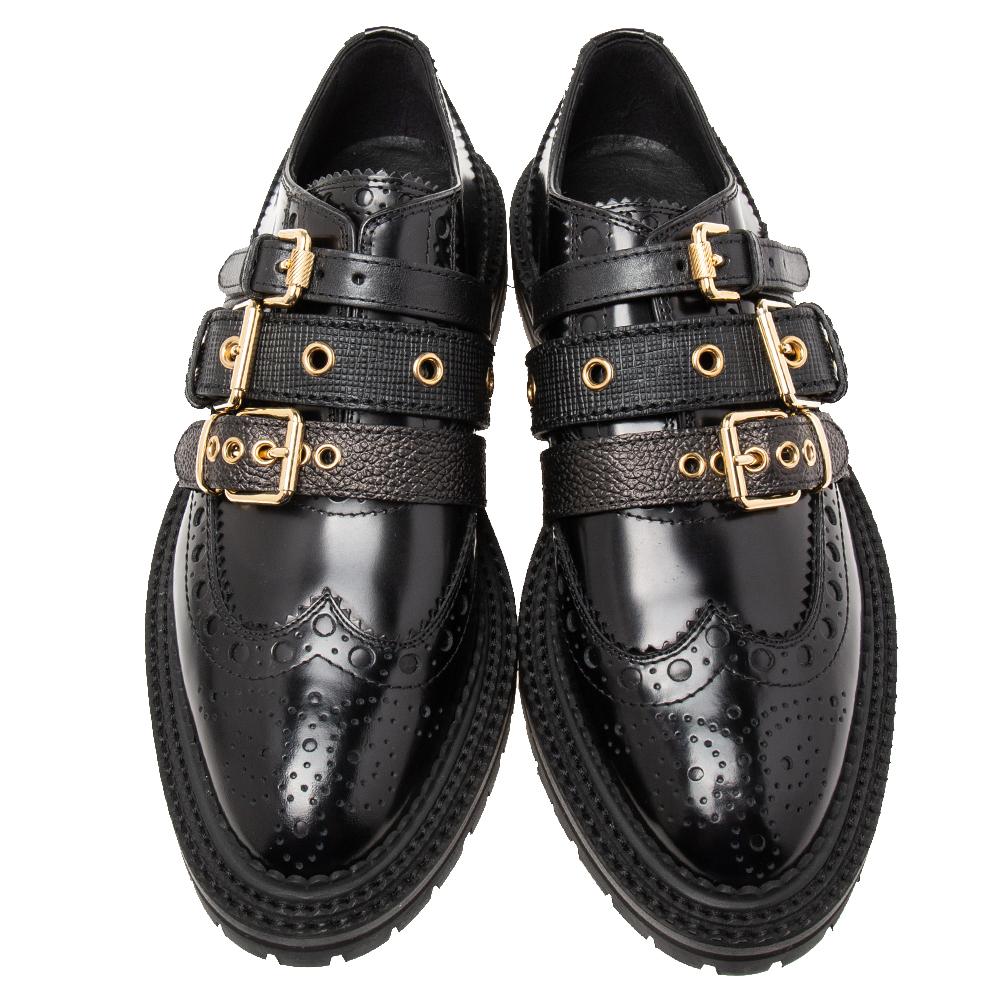Brimming with excellence and expertise, these Doherty Brogues from the House of Burberry truly embody the fine art of shoemaking. They are designed using black patent leather, with multiple strap embellishments placed on their vamps. They come with
