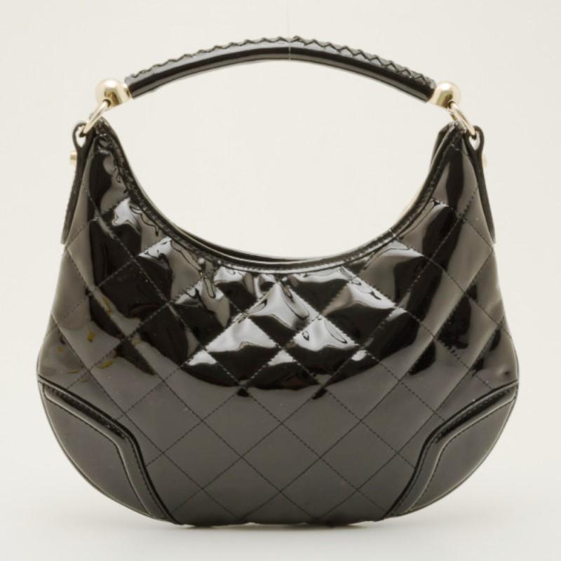 You’ll love carrying this sleek Black Patent Quilted Hoxton Hobo that mixes classic Burberry design with edgy finishing. This quilted style hobo is made from glossy patent leather, with contrasting trim that is accented with a gold Burberry knight