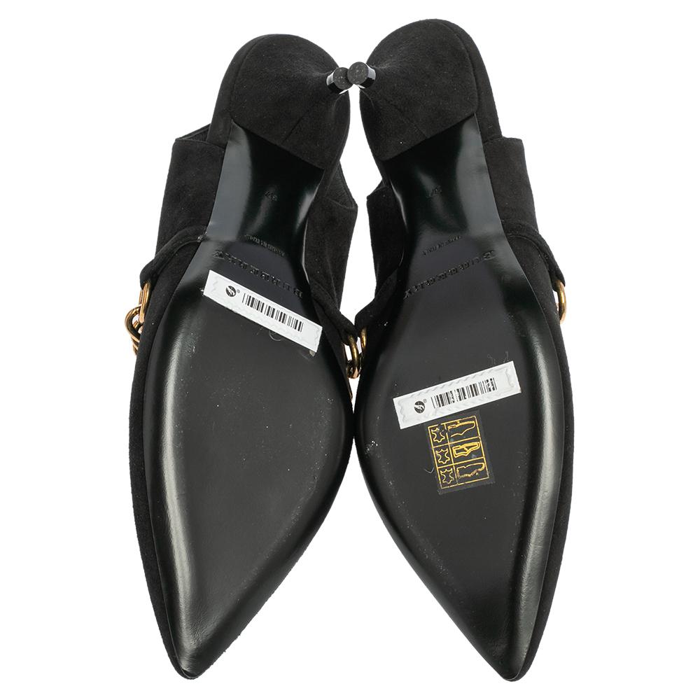 A feminine flair, sleek cuts, and a timeless appeal characterize these stunning Burberry pumps. Skillfully crafted from black suede, they are designed into a pointed-toe silhouette and adorned with chain links. The pumps are raised on low heels and