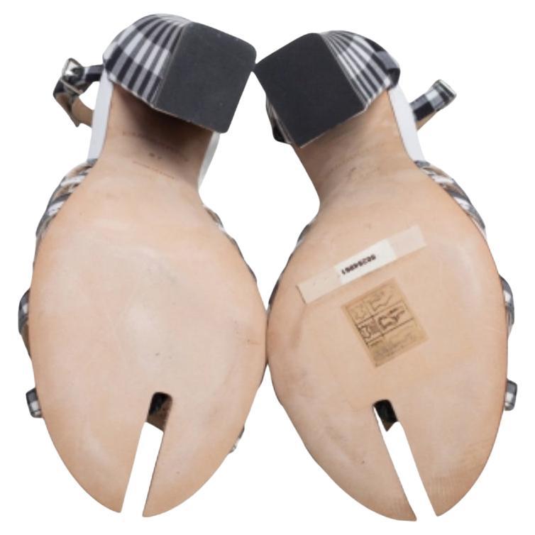 Les sandales Burberry sont conçues en toile et en cuir à carreaux noirs et blancs et sont dotées de brides à l'avant et à la cheville. Les sandales sont embellies par des talons blocs et des détails fendus au niveau des orteils.
