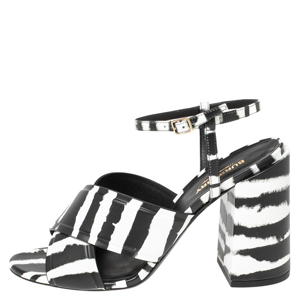 A feminine flair, sleek cuts, and a timeless appeal characterize these stunning Burberry sandals. Crafted from leather in black and white shades, they are designed with crisscrossed straps, secured with ankle straps, and raised on block heels  These