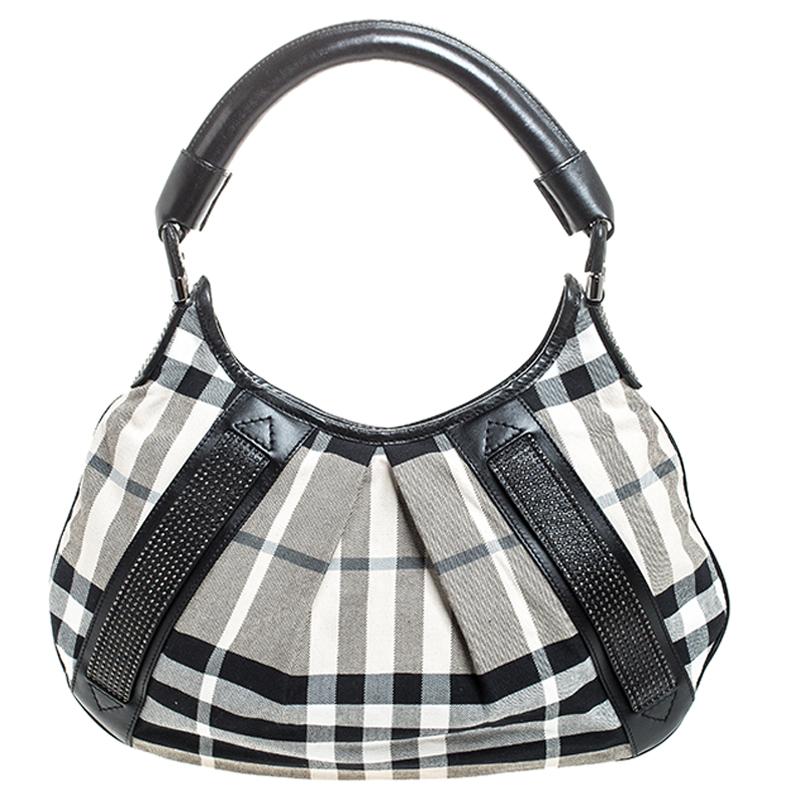 This stunning Phoebe hobo bag from the house of Burberry has a stylish silhouette. It is crafted in Italy and is made of leather and the brand's house check canvas. It flaunts back and white hues and is hed by a single strap. The exterior is