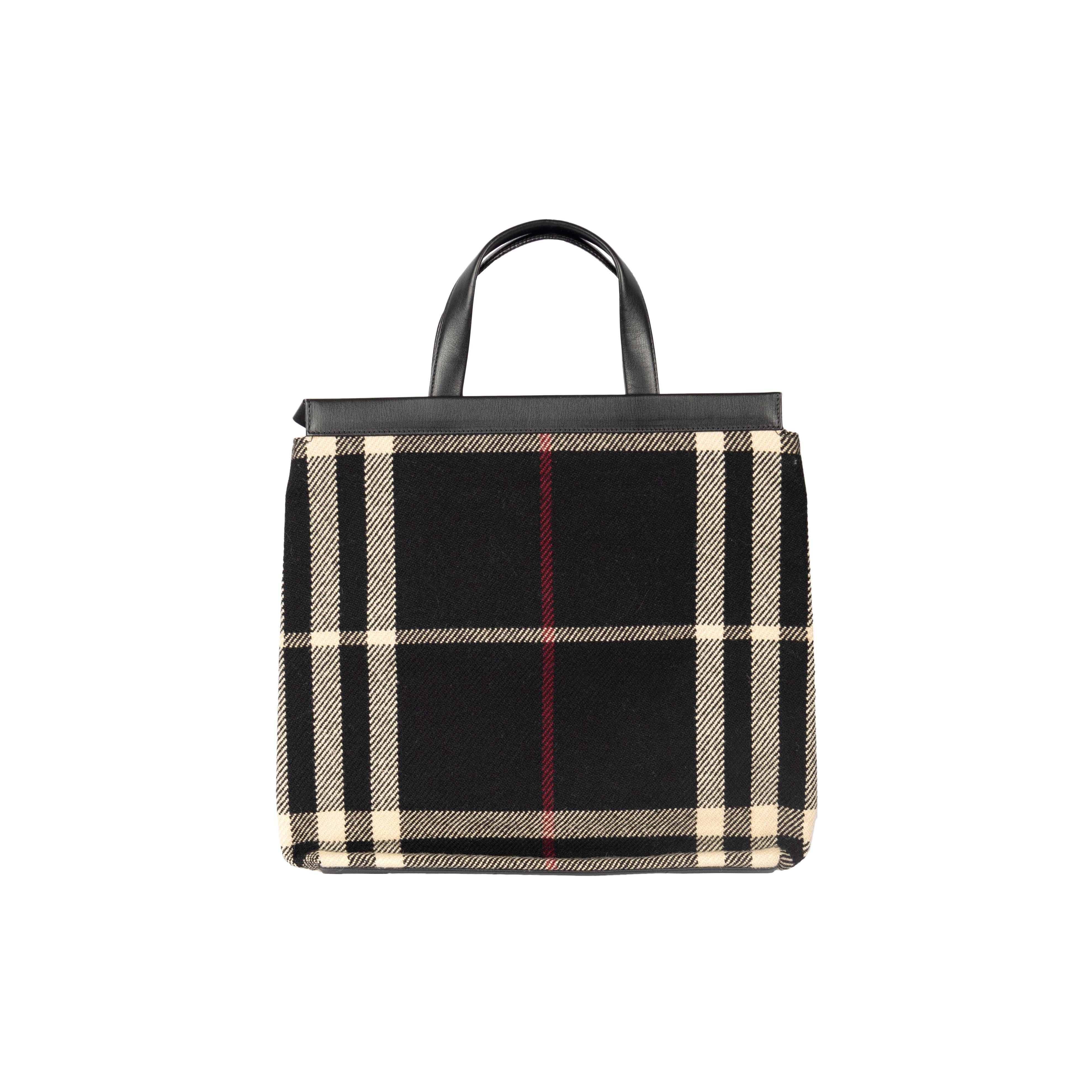 The Burberry Blanket Tote features the brand's signature plaid design in black with a burgundy inner lining. Attached on the inner side is a wide brown pocket adorned with the brand label that is perfect to store small essentials.

