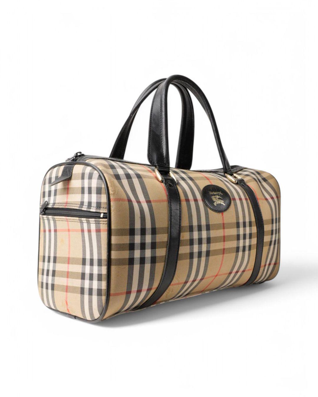 Burberry signature bag, Boston model, made of multicolor Check patterned fabric and brown leather inserts with gold hardware. Equipped with a top zipper closure and internally lined with black leather, the bag is very roomy. Equipped with double