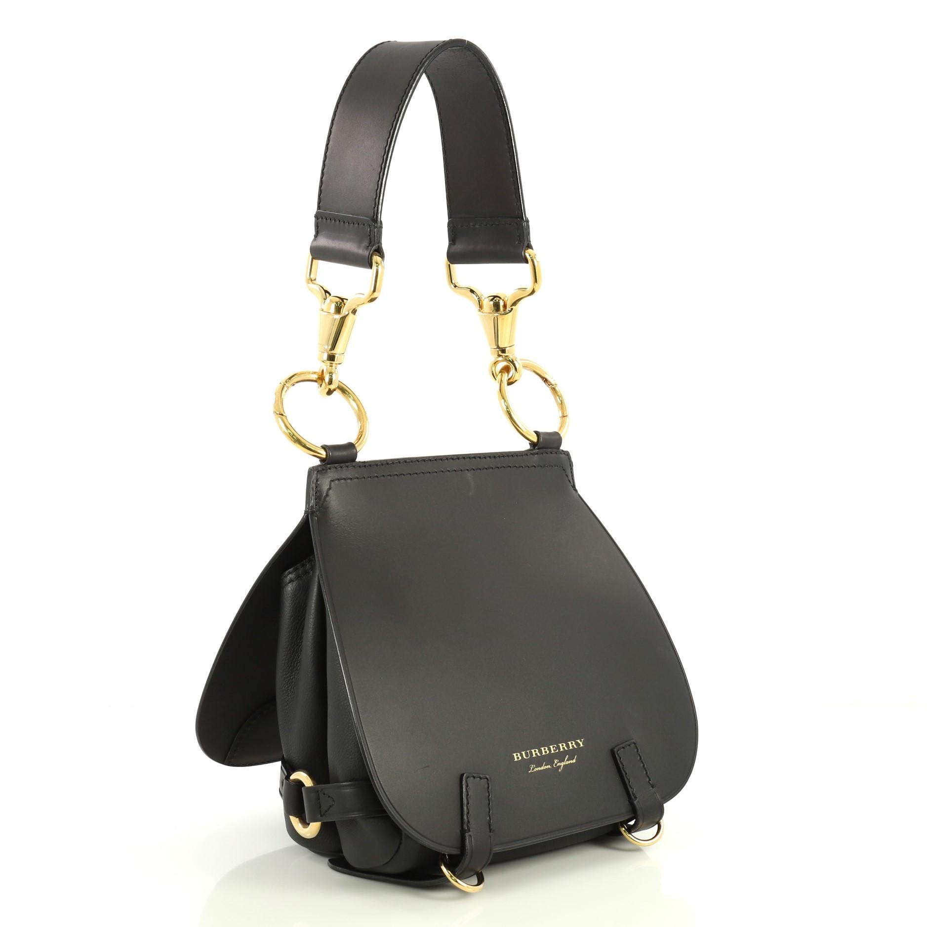 This Burberry Bridle Handbag Leather Medium, crafted from black leather, features leather top handle, front flap compartment with D-ring closure, back flap compartment with magnetic closure and gold-tone hardware. It opens to a black microfiber