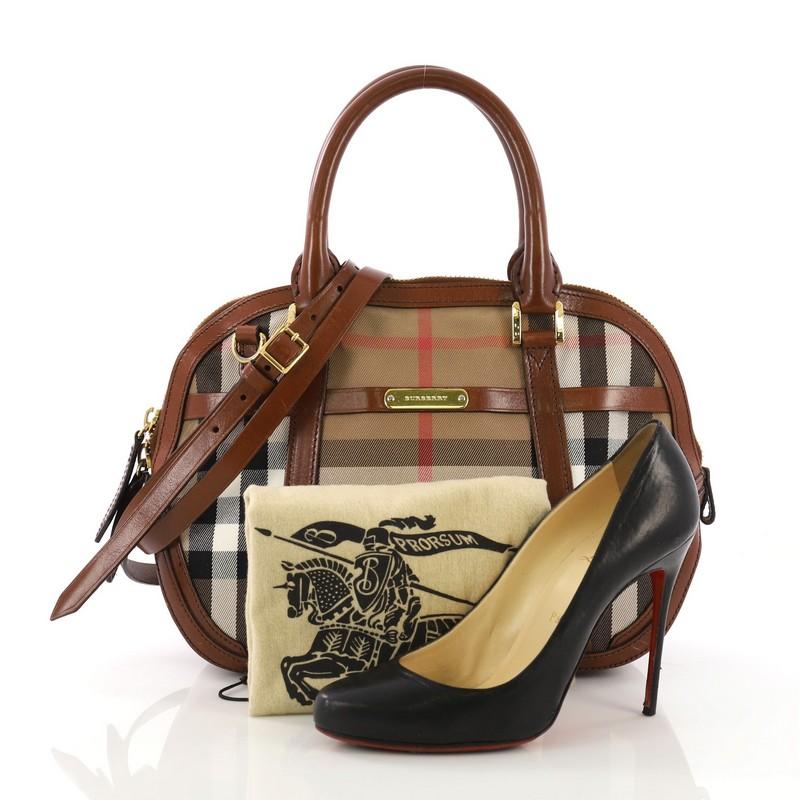 This Burberry Bridle Orchard Bag House Check Canvas Small, crafted from brown house check canvas, features dual rolled leather handles, full leather base and bottom corners, engraved logo plate, protective base studs, and gold-tone hardware. Its zip