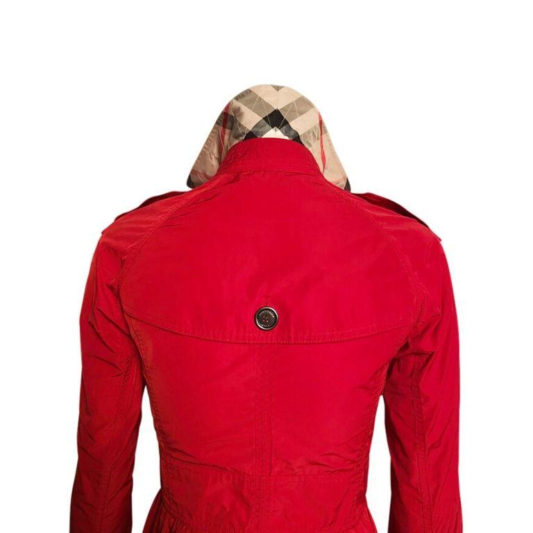 The cutest Burberry Brit fire engine red mini trench coat. This stirking coat features Burberry Britt gunmetal buttons and hardware, classic Burberry check print fabric in upper back interior and underneath collar, and gorgeous peplum cut.
