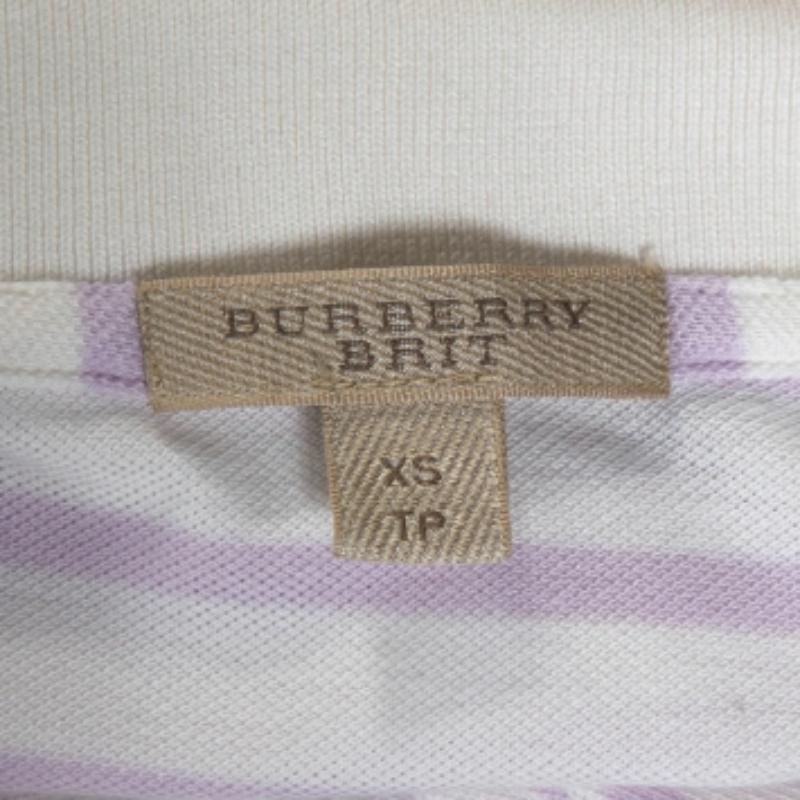 Questa polo di Burberry Brit è realizzata in misto cotone. Si presenta in una tonalità bianco sporco con un motivo a righe su tutta la superficie, un colletto semplice, maniche corte e bottoni. La camicia è elegante e confortevole.