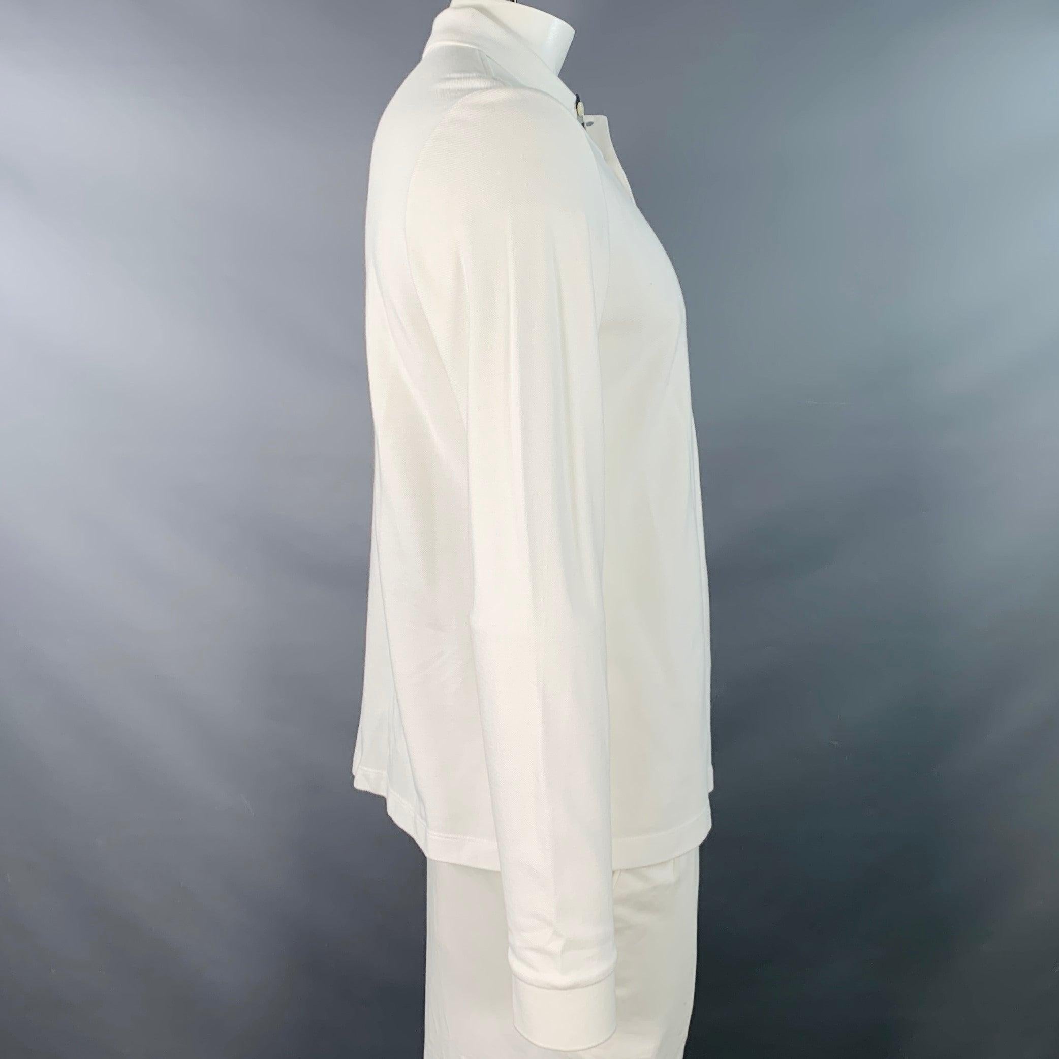 Polo BRIT de Burberry
en piqué de coton blanc avec logo brodé taupe, manches longues et demi-patte boutonnée avec bordure écossaise signature. Très bon état d'origine.
 Marques et signes d'usure mineurs. 

Marqué :   L 

Mesures : 
 
Épaule : 17