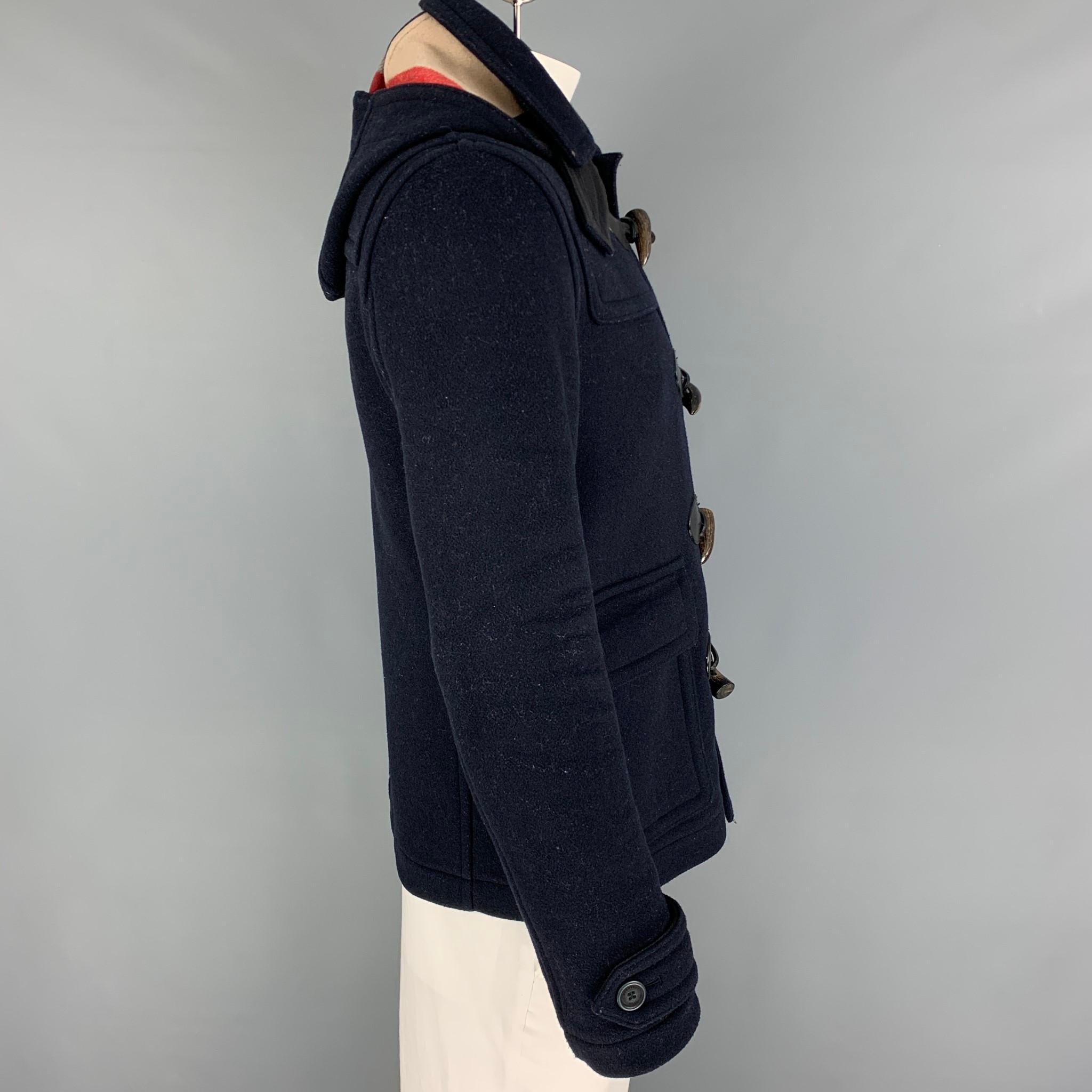 BURBERRY BRIT coat comes in a navy wool / polyamide with a plaid lining featuring a hooded style, flap pockets, and a toggle button closure. 

Very Good Pre-Owned Condition. Moderate wear throughout. As-is.
Marked: M

Measurements:

Shoulder: 18.5