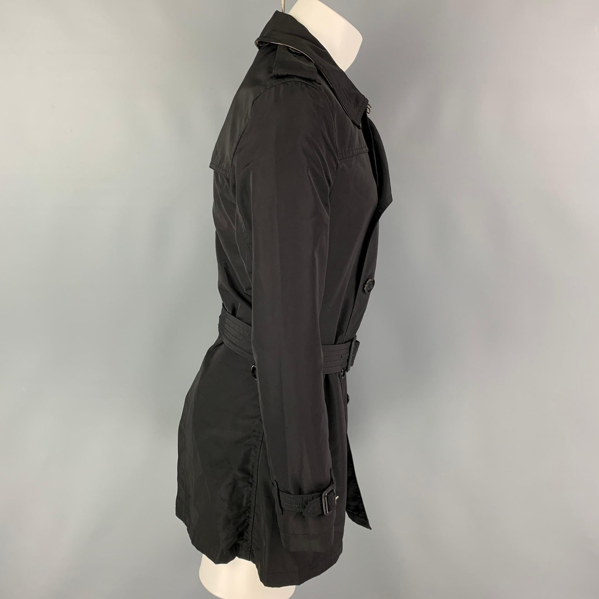 BURBERRY BRIT trench coat comes in a black nylon with a plaid interior featuring a belted style, epaulettes, front pockets, and a double breasted closure. 

Very Good Pre-Owned Condition.
Marked: S

Measurements:

Shoulder: 17 in.
Chest: 36