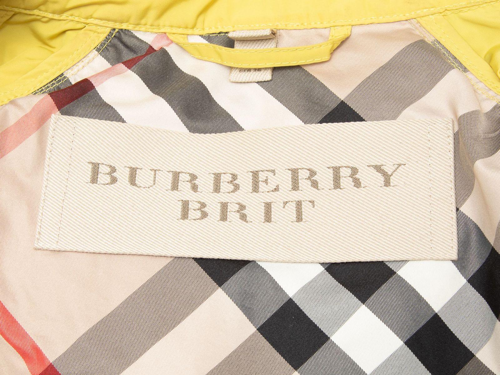 Product Details: Yellow nylon hooded jacket by Burberry Brit. Dual hip pockets. Button closures at front. 34