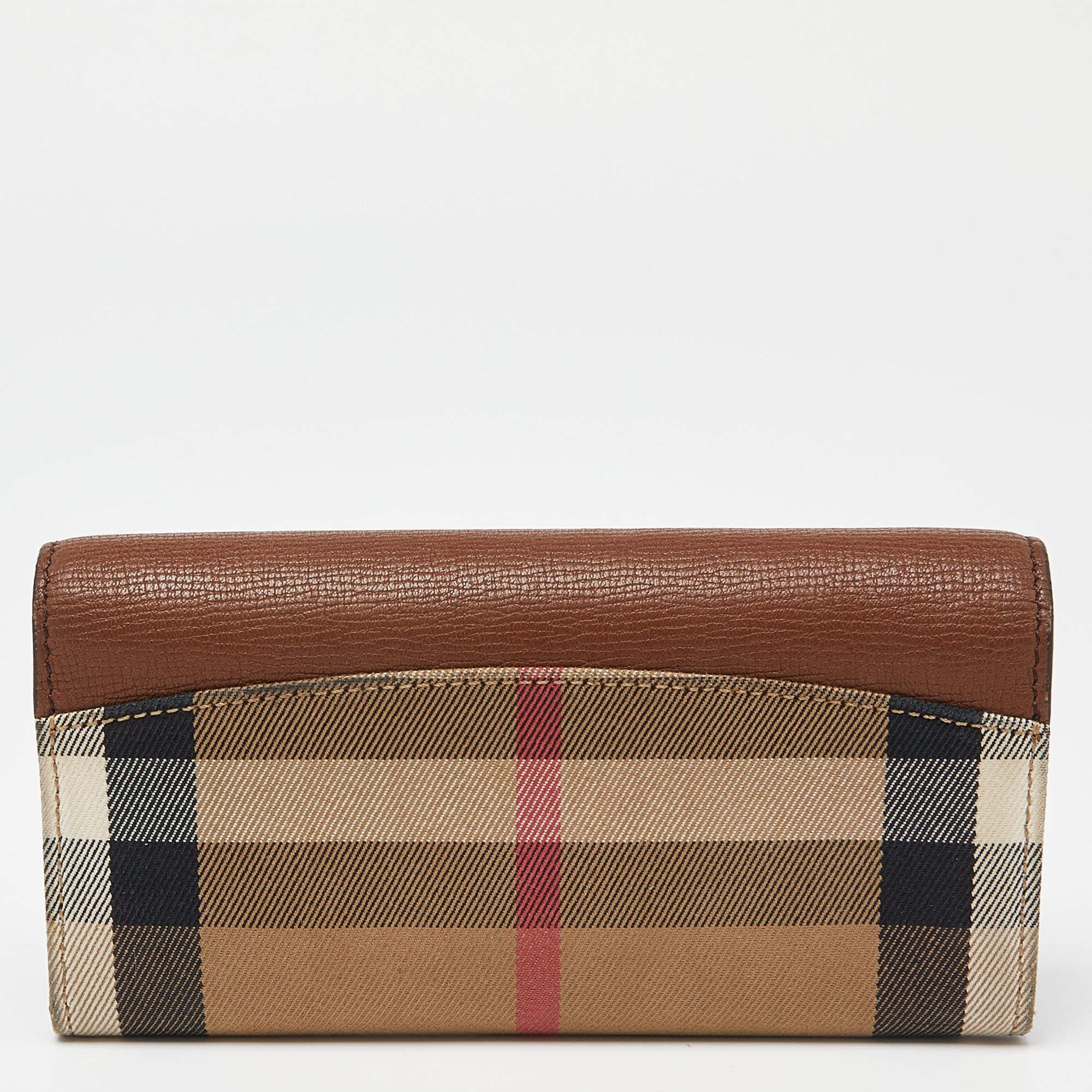 This Burberry continental wallet is crafted from Check canvas and leather. The front flap has a buttoned closure that opens to a well-sized interior having two open compartments and slip pockets for you to arrange your cards and bills securely.