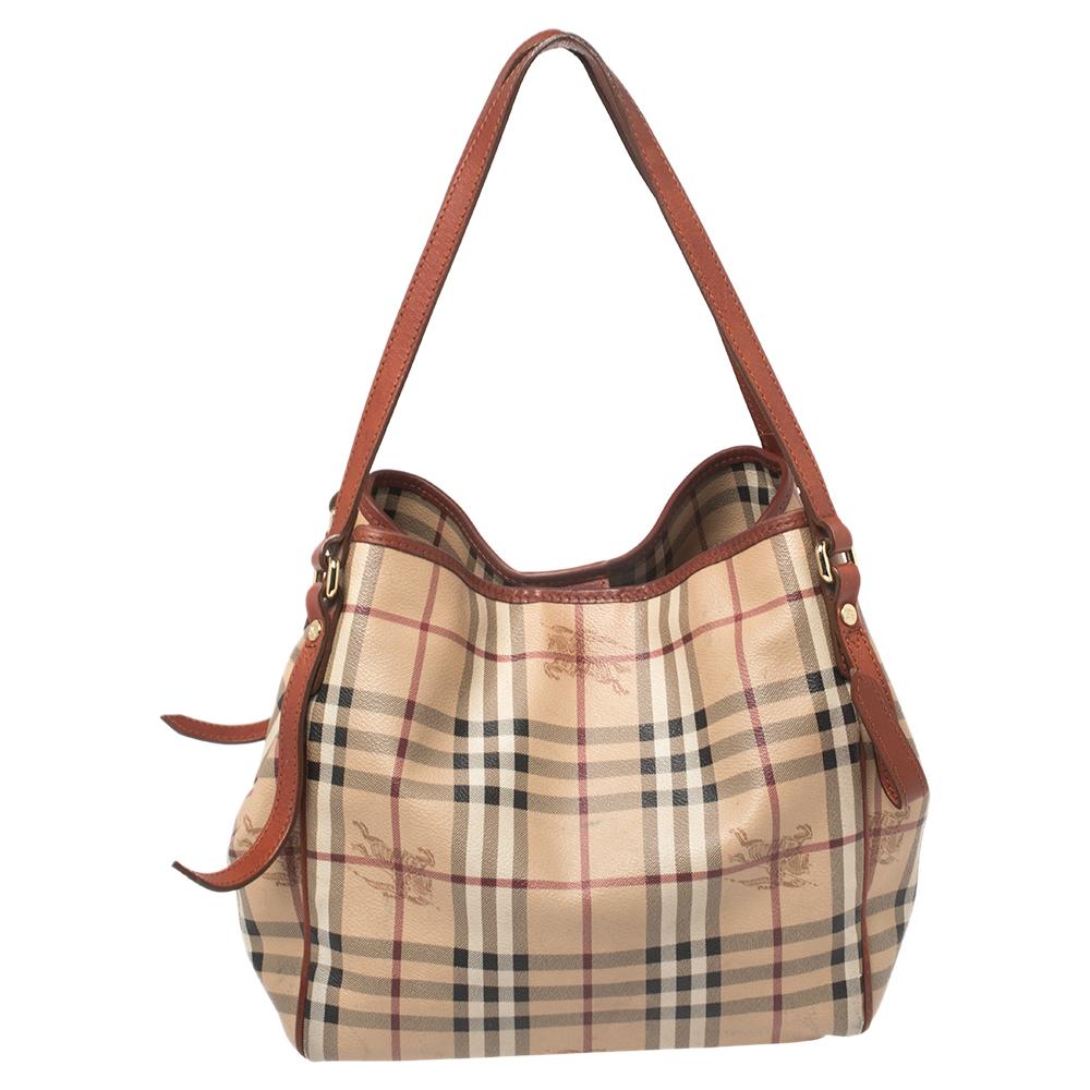 This Canterbury tote from Burberry is crafted from House check coated canvas and leather. It comes with dual flat handles, protective metal feet, and a spacious interior that can hold all your daily necessities. Simple in design, the bag is perfect