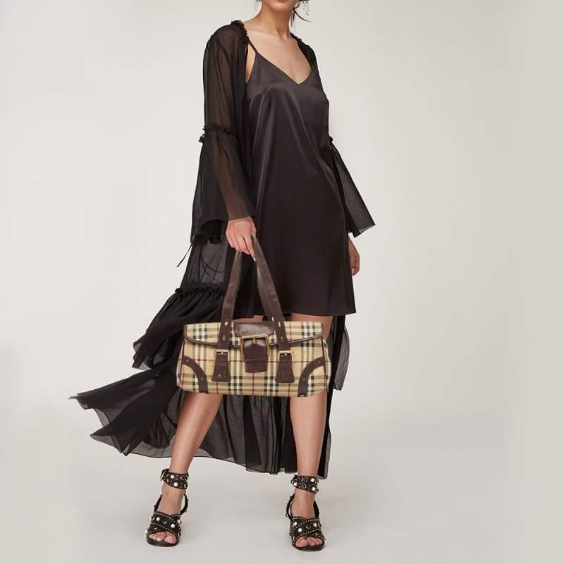 This Burberry shoulder bag is a must have. Crafted meticulously from the brands House check PVC and leather it comes in beige and brown hues. It has a single shoulder strap a front flap with a buckle closure that leads to a spacious canvas lined