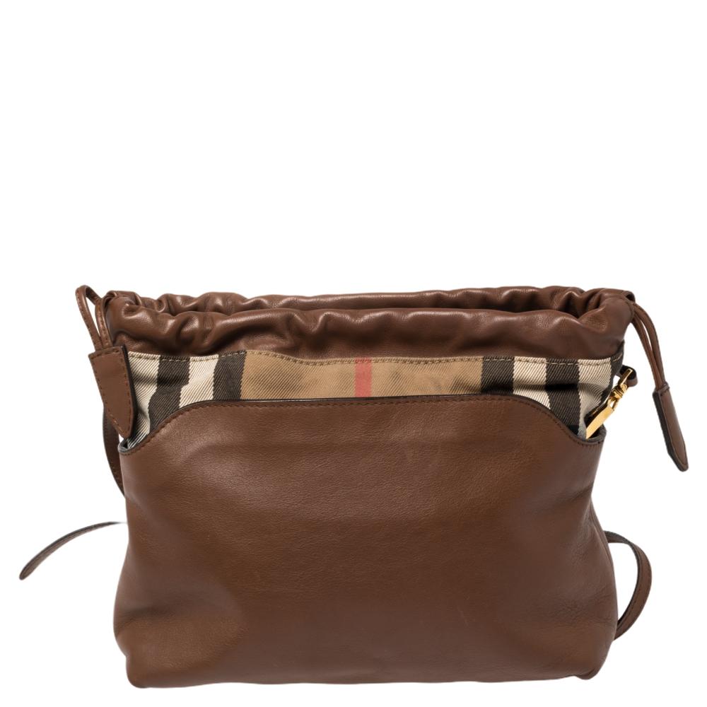 From the house of Burberry, Little Crush is an outstanding fusion of elegance and style. Made in brown leather, it is styled with signature House check canvas trim and held by a shoulder strap. The drawstring closure secures a durable canvas
