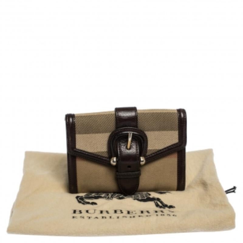 Dieses kompakte Portemonnaie stammt aus dem Hause Burberry. Sie ist aus Nova-Karo-Canvas und Leder gefertigt. Sie hat eine Schnalle auf der Vorderseite und ist in Braun- und Beigetönen gehalten. Sie hat eine Innenausstattung aus Leder und Stoff mit