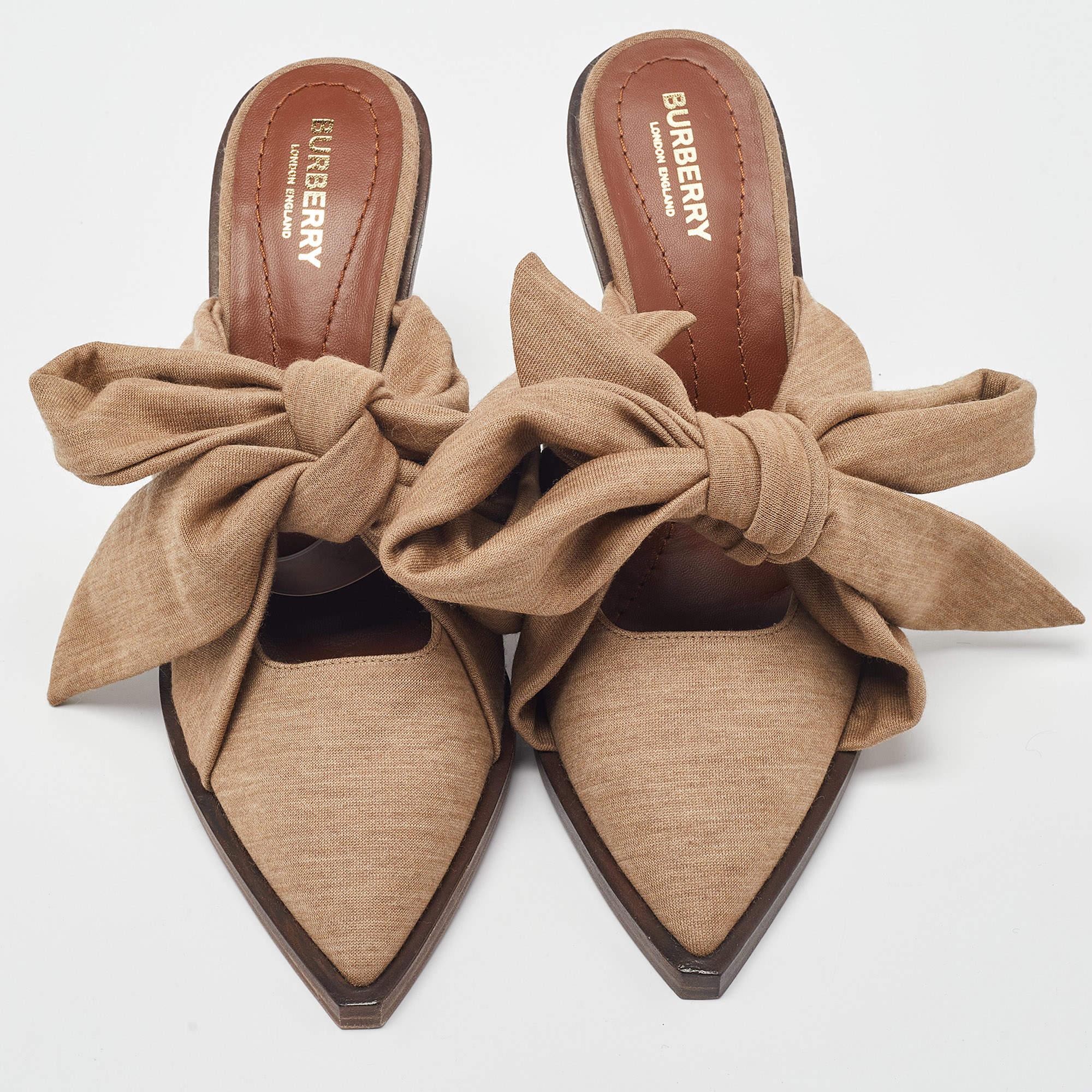The Burberry mules are elegant and luxurious footwear. Crafted with rich brown fabric, they feature a stylish scarf tie detail that adds a touch of sophistication. These mules effortlessly blend comfort and style, making them a versatile choice for