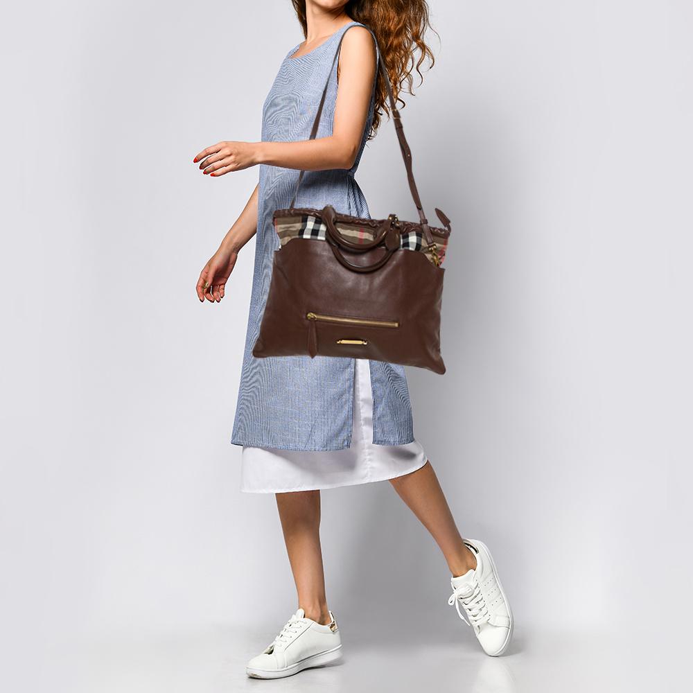 From the house of Burberry, this Big Crush tote is an outstanding fusion of elegance and style. Made in leather, it is styled with a house check canvas panel on the top, a zip pocket at the front, and held by twin top handles as well as a shoulder
