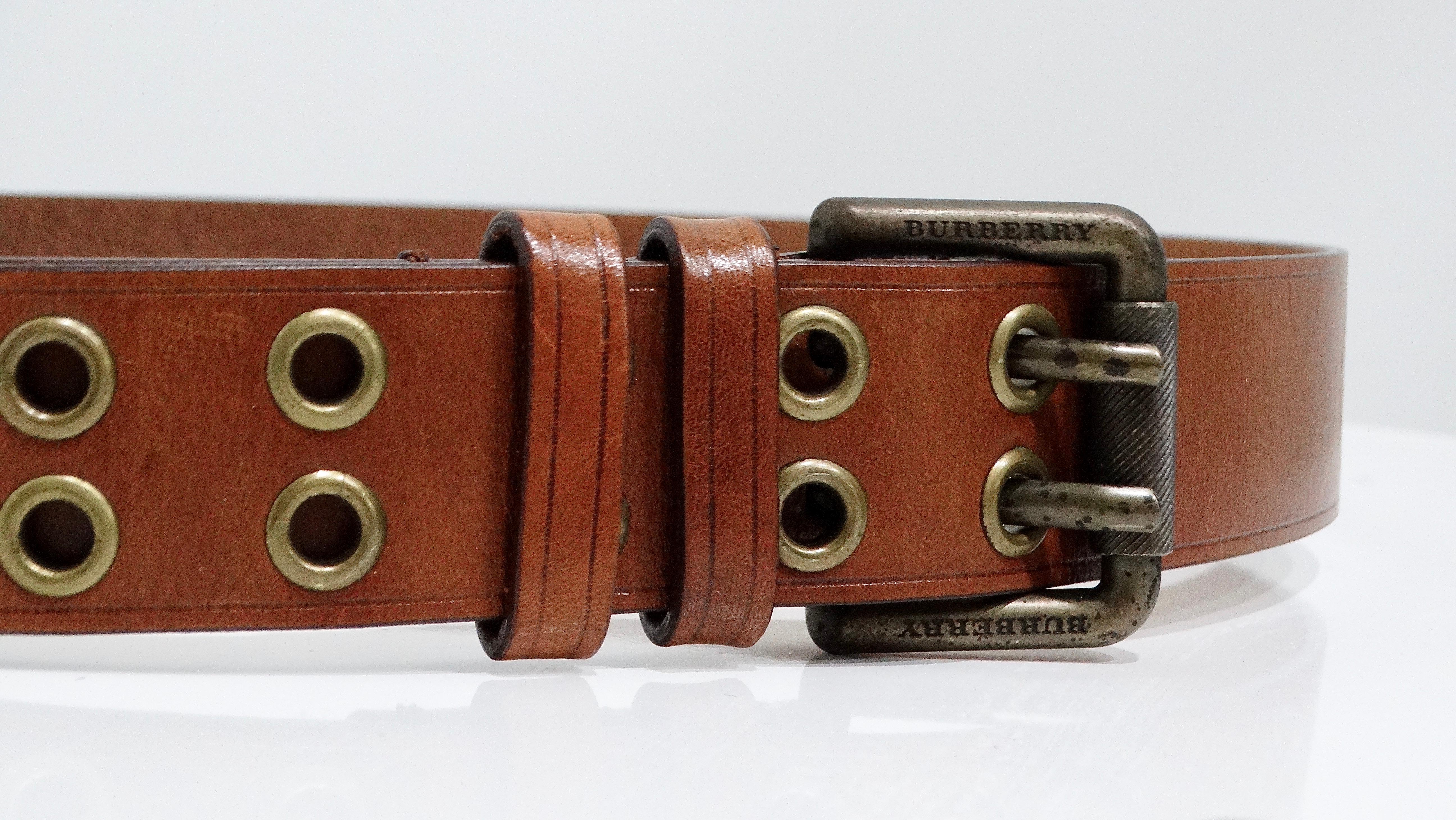The brown Burberry leather belt is a refined yet casual accessory, crafted with precision in Italy. Featuring brass hardware and a distinctive double grommet design, this belt embodies both durability and style. The rich brown leather paired with