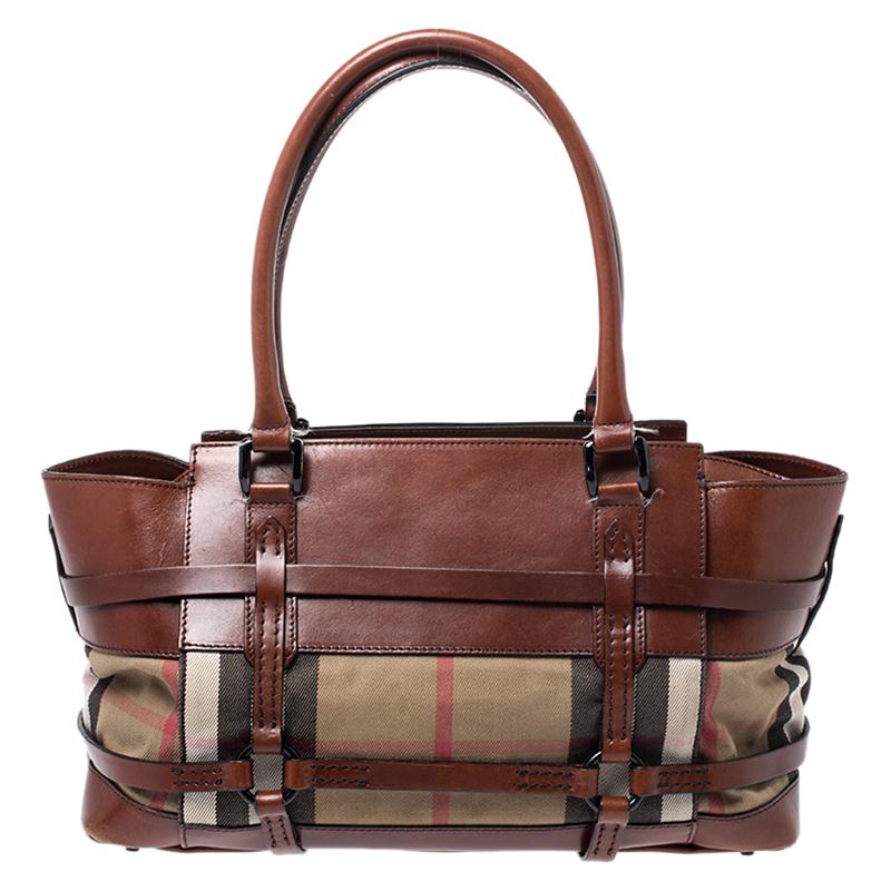 Spacious and captivating, this Bridle satchel is from Burberry. It has been crafted from their signature House check coated canvas and accented with leather trims and black-tone hardware. It is equipped with a well-sized canvas interior, two rolled