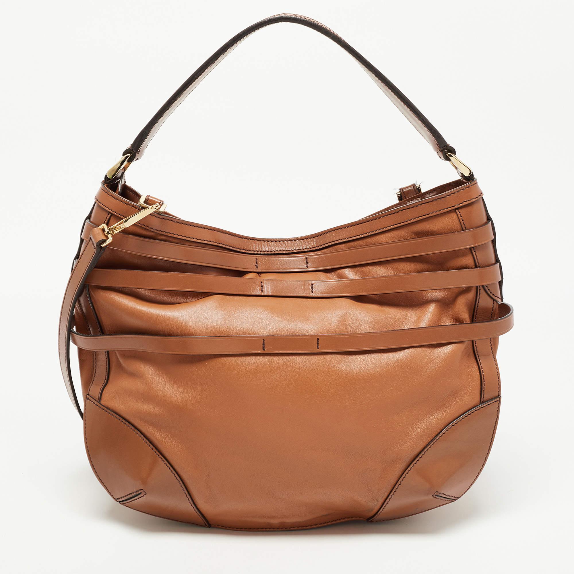 This stylish hobo from Burberry has been crafted from brown leather. The zip-top closure opens to a nylon-lined interior that is spacious enough to hold your everyday essentials. The bag comes with different handles and belt detailing.

Includes: