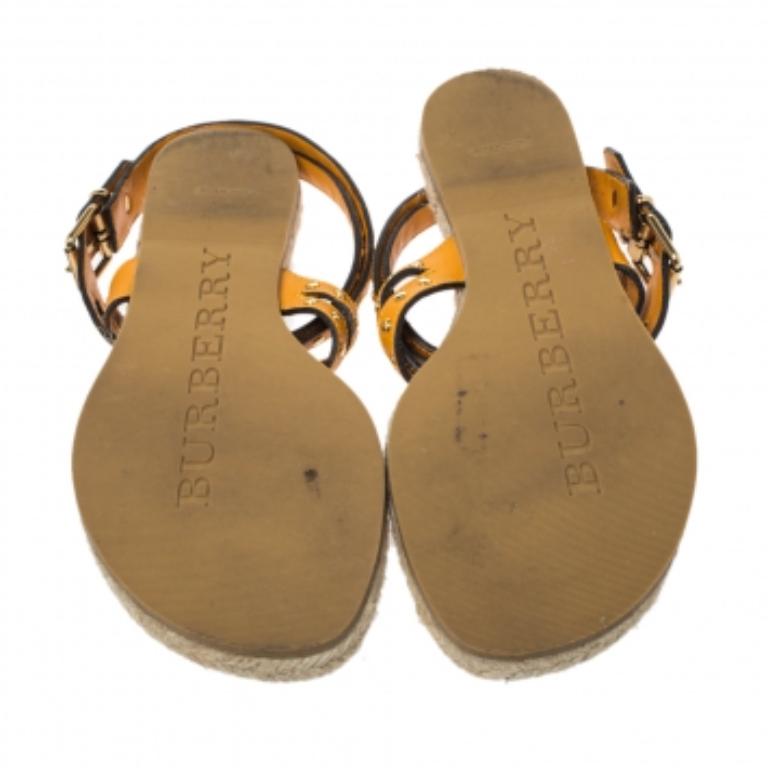 These smart and trendy flats from Burberry are crafted from brown and mustard yellow leather and feature a thong design. They have been styled with gold-tone studded cross ankle straps and come equipped with jute insoles. They are complete with