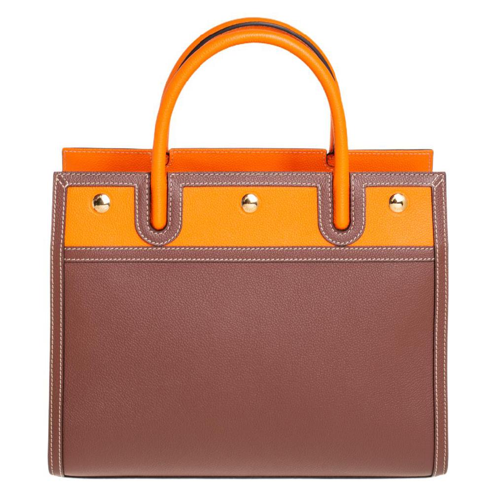 Burberry's finest range of totes includes this beauty here. It is crafted in a structured silhouette using brown/orange leather and held by two top handles and a detachable shoulder strap. The designer tote has a spacious interior and gold-tone