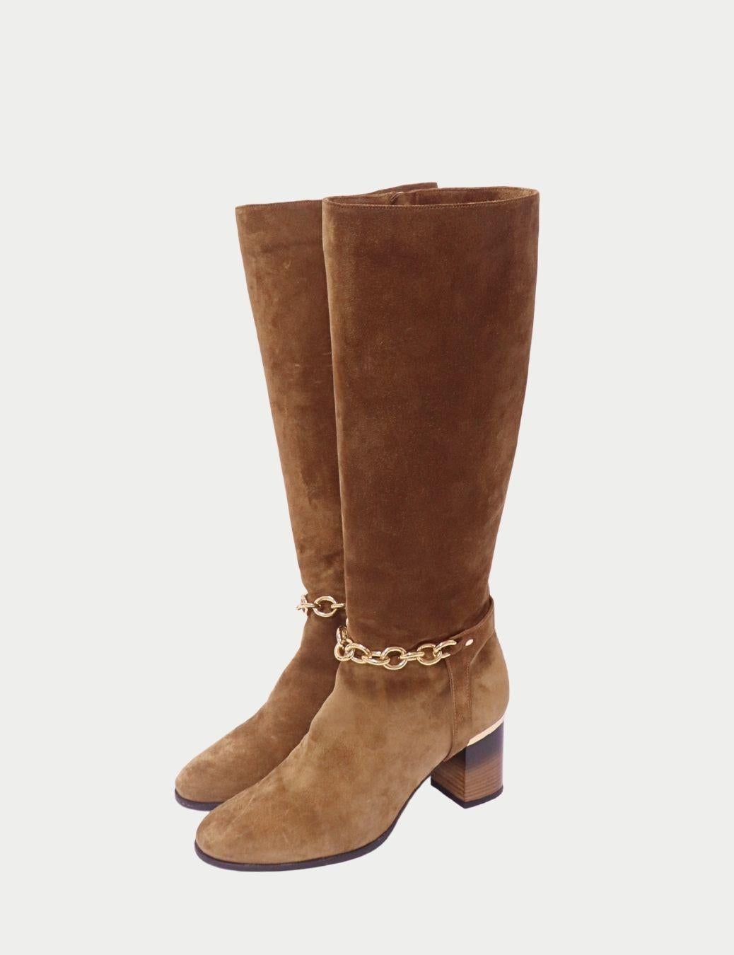 Botas Burberry a media caña de ante marrón con detalle de cadena dorada

Adéntrate en la elegancia atemporal con estos botines Burberry de ante marrón, confeccionados en suave y lujoso ante y acentuados con una pulida cadena dorada alrededor del