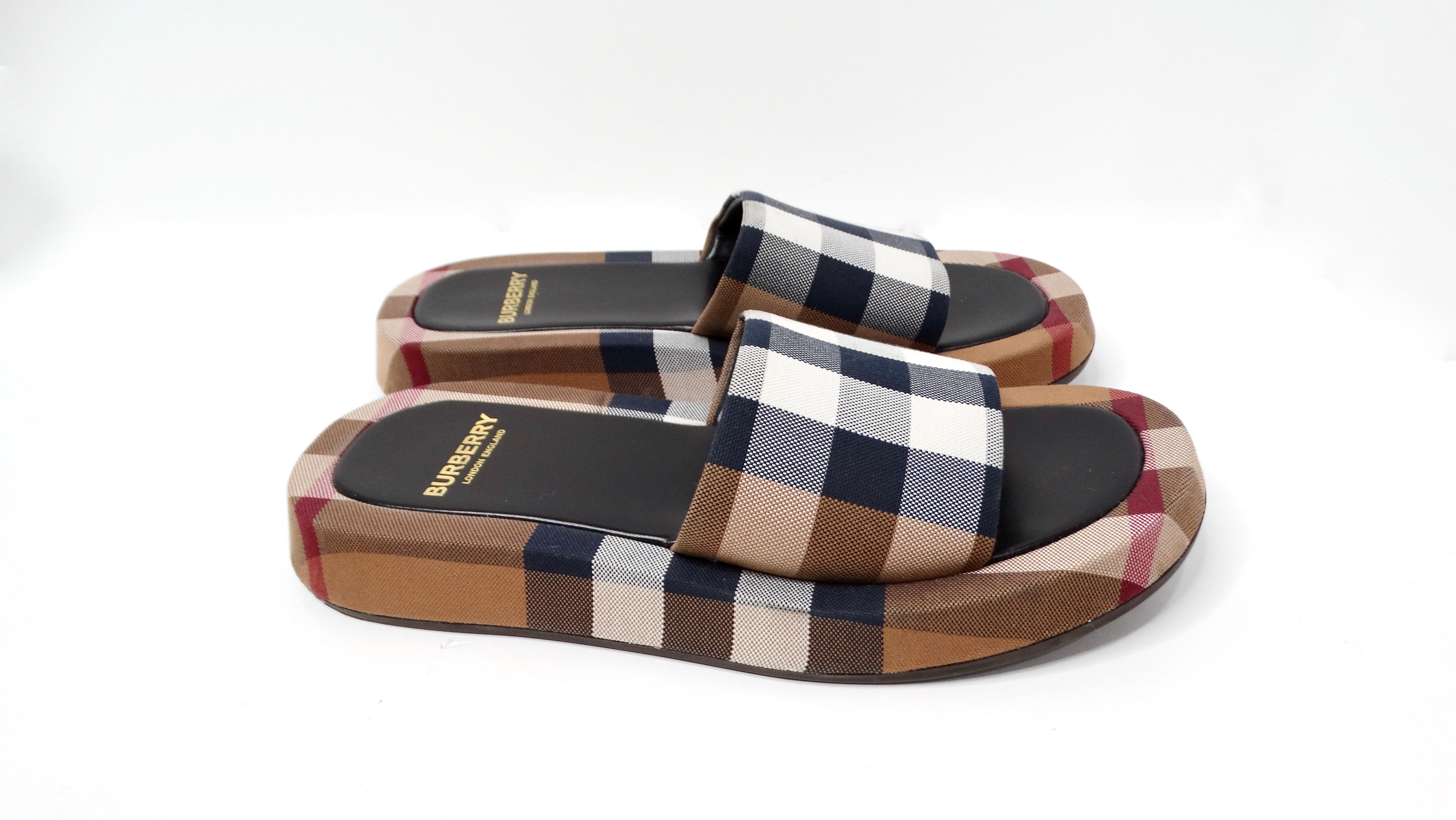 Les sandales coulissantes à plateforme à carreaux Buckingham de Burberry constituent un ajout chic et élégant à toute garde-robe estivale. Fabrice présente le motif à carreaux bleu marine et marron emblématique de Burberry. Confectionnées en coton