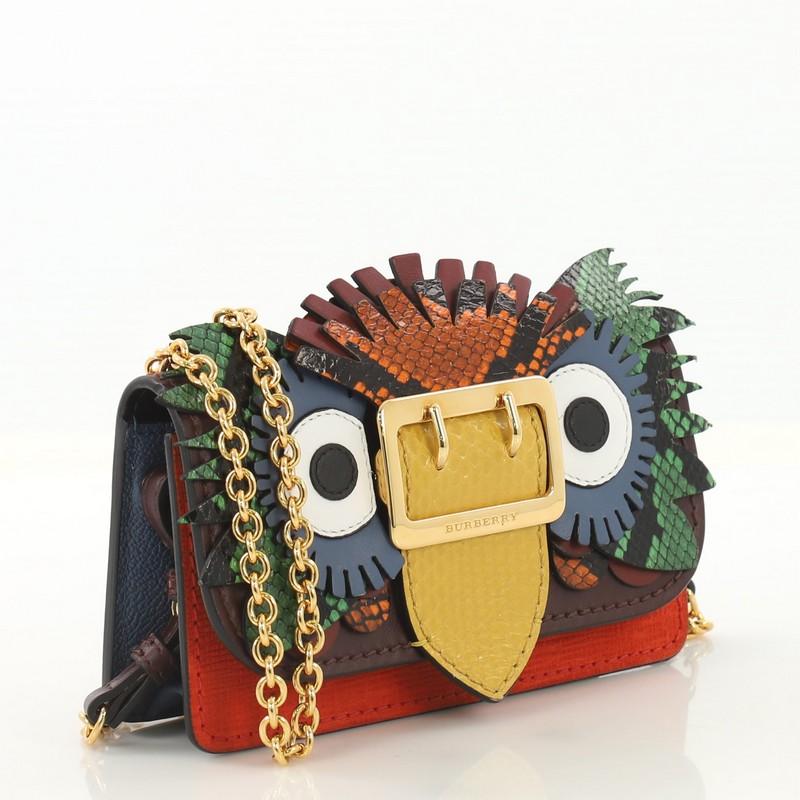 This Burberry Buckle Chain Wallet Leather with Snakeskin and Applique Mini, crafted from multicolor leather with genuine snakeskin, features a chain link strap, leather owl applique, and gold-tone hardware. Its magnetic snap closure opens to a black