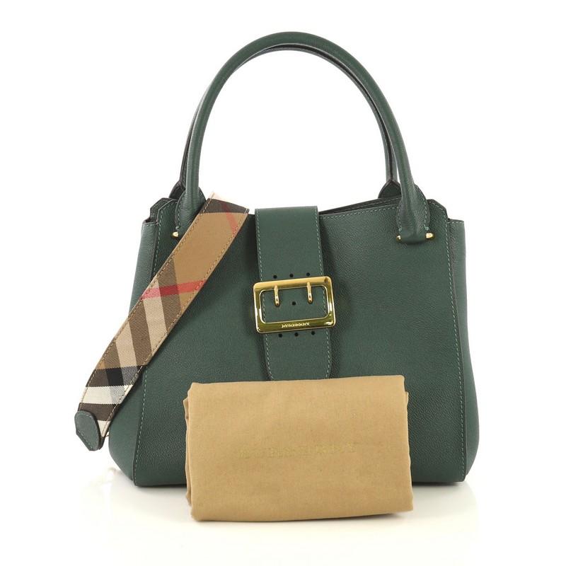 This Burberry Buckle Tote Leather Medium, crafted from green leather, features dual rolled leather handles, flap tab with buckle detail, protective base studs, and gold-tone hardware. Its magnetic snap button closure opens to a brown house check