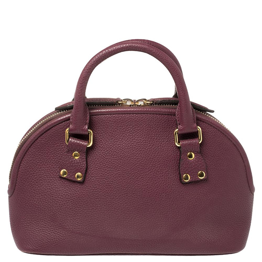 Expertly crafted and skillfully designed, this Burberry creation is a must-have in every woman's collection. It is made from grained burgundy leather and features two handles and a spacious fabric interior. Ideal for any day, this sophisticated bag