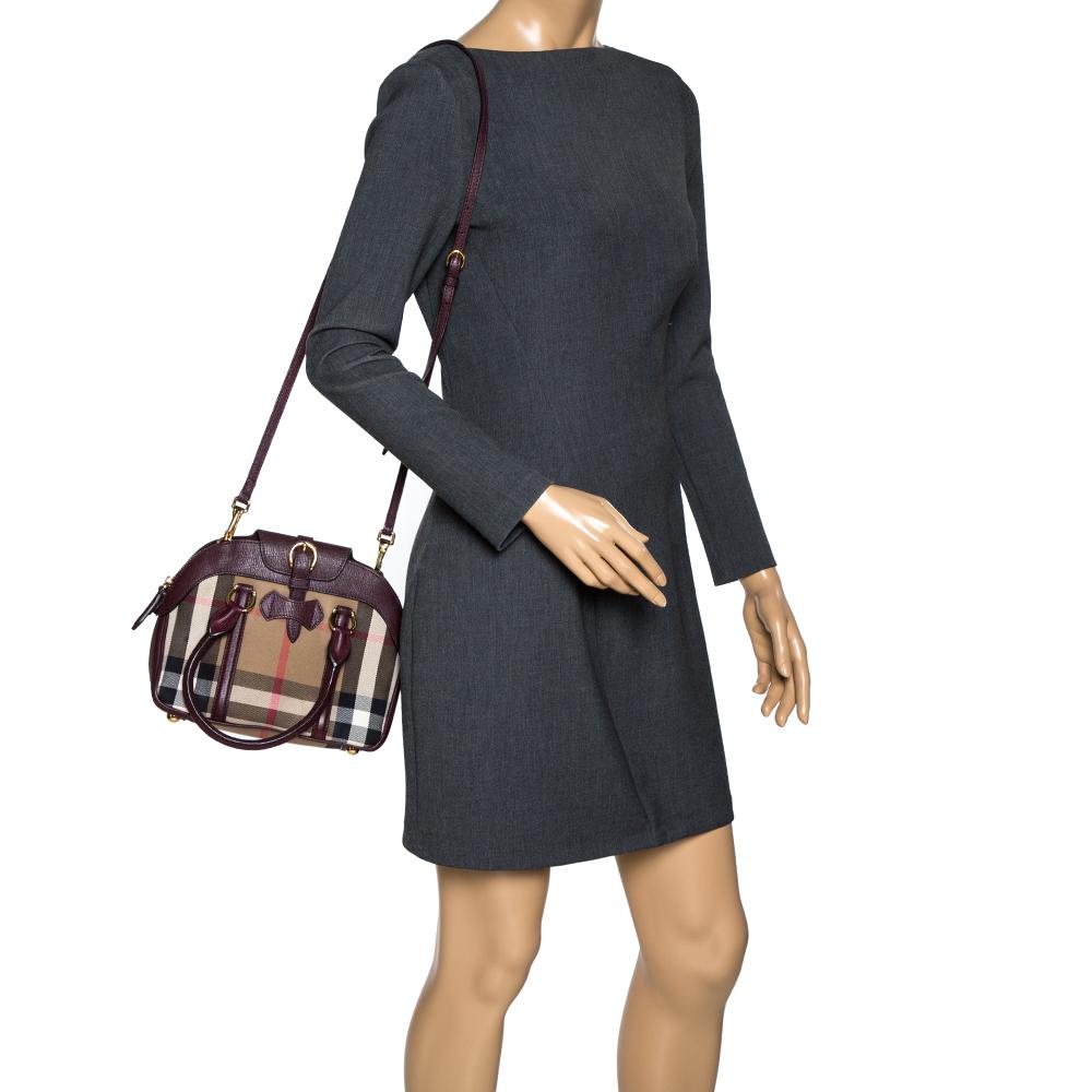 This Milverton satchel comes from the house of Burberry. Crafted from house-check canvas and leather, it comes in burgundy hues. It has dual handles, buckle detailing, zip closure, and fabric-enclosed exterior. It has gold-tone hardware and a
